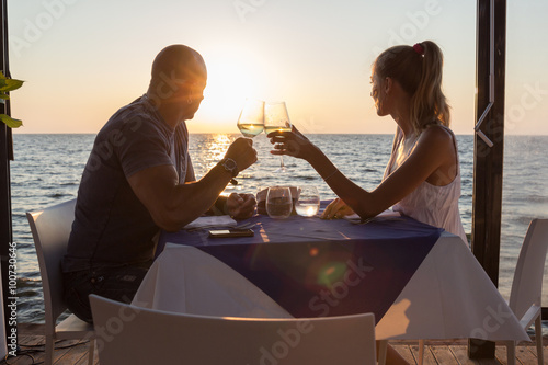 Couple watching sunset dining in sea restaurant