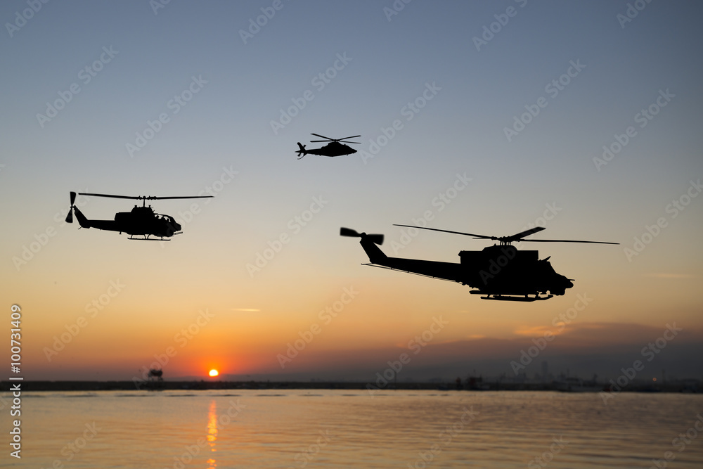 Three flying army helicopters on sunset background