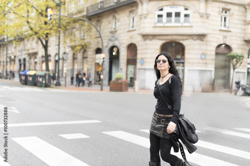 Woman with sunglasses heavy metal style walking in the street. Woman with sunglasses heavy metal style walking in the street.