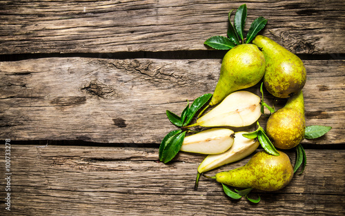 Fresh pears with leaves. On wooden background.