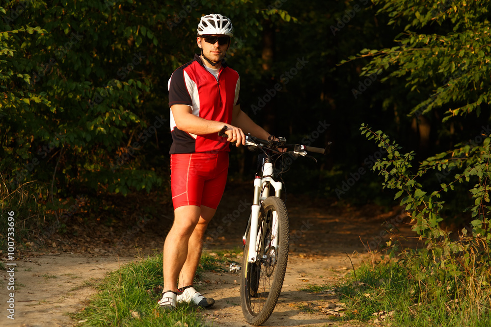 Fototapeta premium Cyclist riding mountain bike on trail at evening.