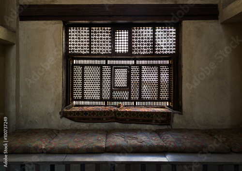Aged interleaved wooden window (Mashrabiya) and a built-in couch photo
