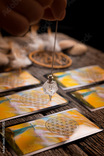 Hand with pendulum over tarot cards