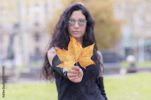 Woman hand holding autumn leaf.