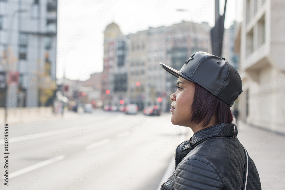 Profile portrait of young woman with baseball cap in the street. Profile portrait of young woman with baseball cap in the street.