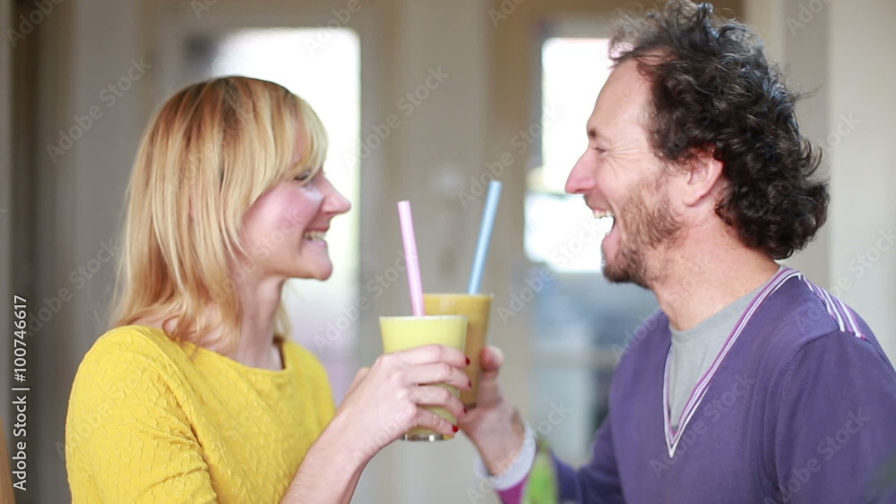 Happy couple toasting and drinking fruit smoothie Happy couple toasting and drinking fruit smoothie