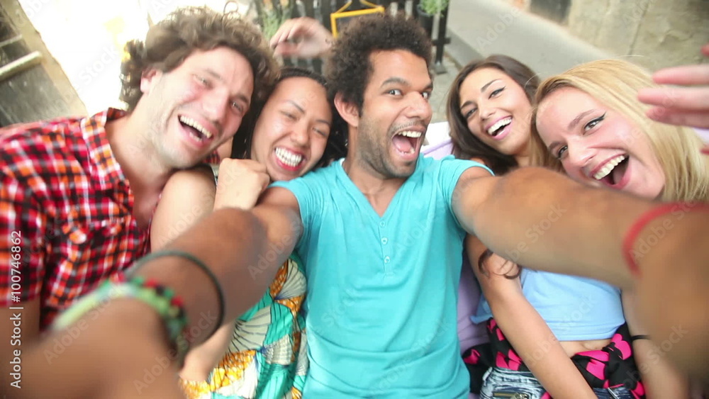 Five young adults laughing while taking a group selfie Five young adults laughing while taking a group selfie