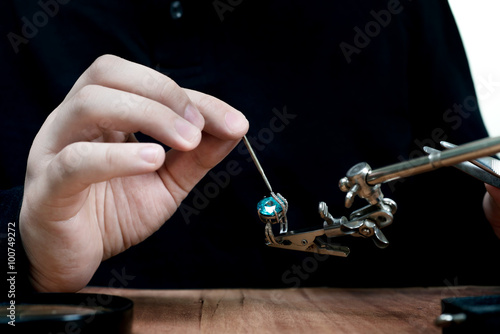 Desktop jeweler. jeweler holding ring with blue stone