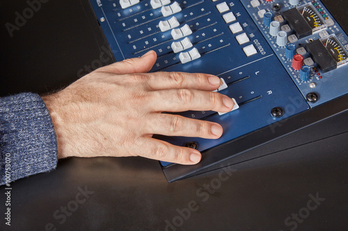 Hand of an audio engineer on a mixing console
