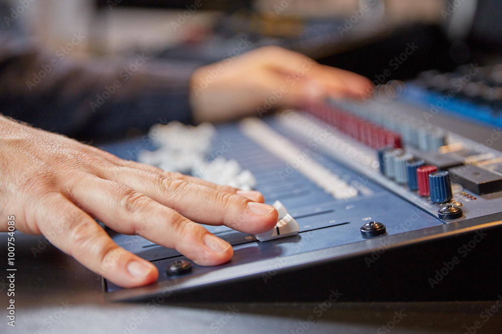 Mixing engineer moving the sliders of audio console