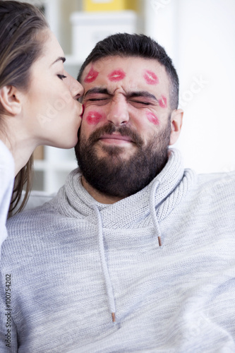 Valentines couple. Woman kissing man with red lipstick all over his face,shallow depth of field