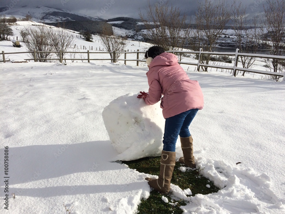 muchacha haciendo una bola gigante para hacer un muñeco de nieve Stock  Photo