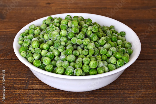 Bowl of frozen peas on wooden table