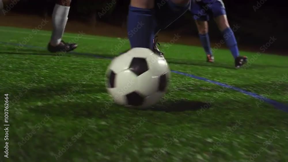 A female soccer player dribbles down the field during a game at night A female soccer player dribbles down the field during a game at night