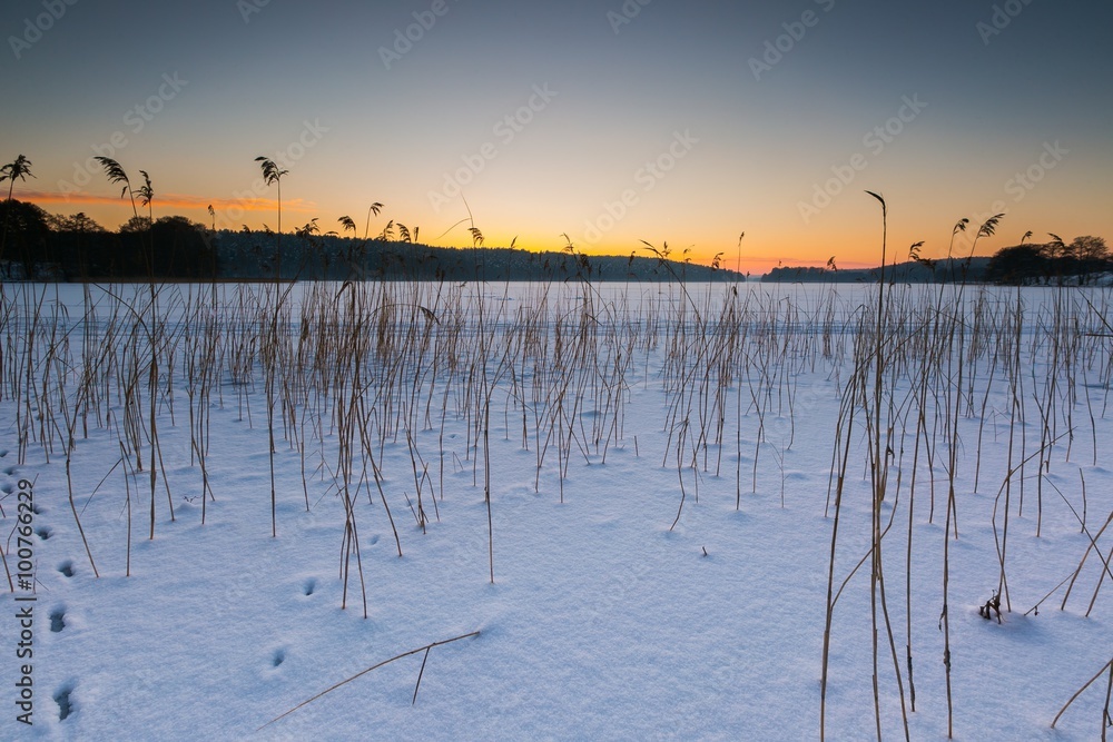 Sunset sky over frozen and snowy lake.