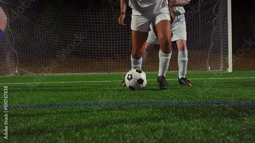 A female soccer player dribbles down the field during a game at night
