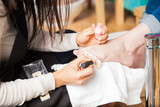 Pedicurist applying nail polish to some toenails
