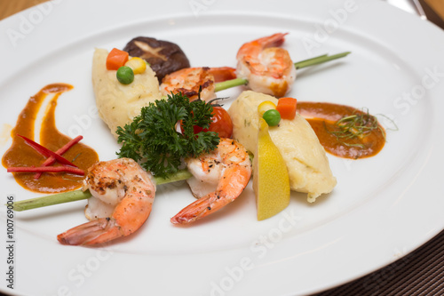 A steak shrimp with fresh with fresh vegetables on a white plat
