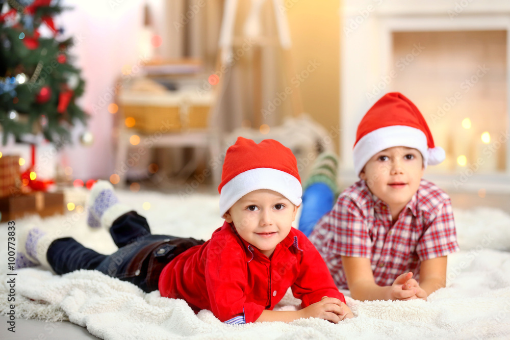 Two cute small brothers lie on carpet on fireplace background Two cute small brothers lie on carpet on fireplace background