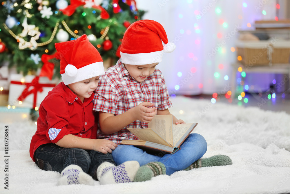 Two cute small brothers reading book on Christmas decoration background Two cute small brothers reading book on Christmas decoration background