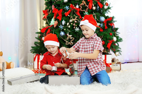 Two cute small brothers opening gifts on Christmas decoration background