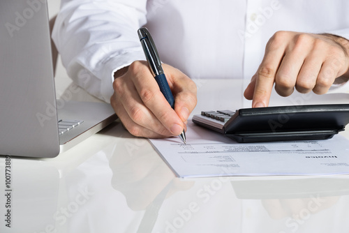 Businessman Calculating Invoice By Laptop