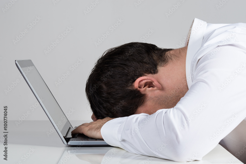 Stressed Businessman Leaning On Laptop At Desk Stressed Businessman Leaning On Laptop At Desk