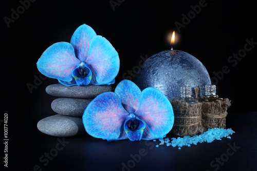 Fototapeta Naklejka Na Ścianę i Meble -  Spa set. Beautiful blue orchid with pile of pebbles, candle, sea salt and aroma oil on black background