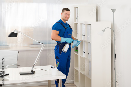 Worker Cleaning Shelf At Office