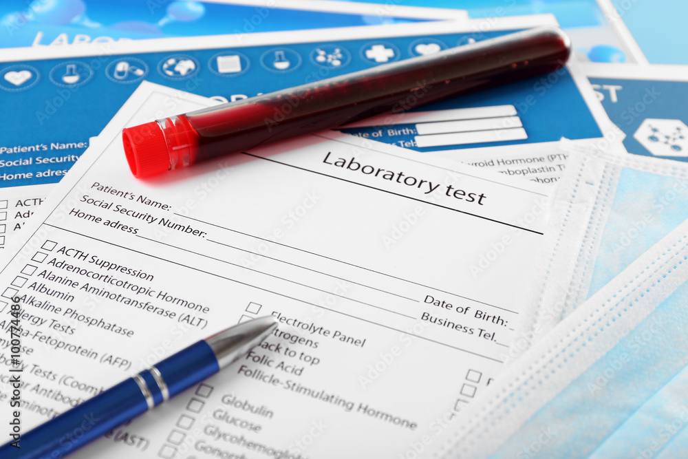 Blood in test tubes, pen and investigation form on the table, close-up Blood in test tubes, pen and investigation form on the table, close-up