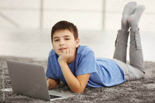 Boy with laptop lying on a ...