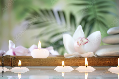 Spa still life with candles in water on natural blurred background