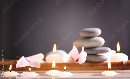 Spa still life with candles in water on grey background