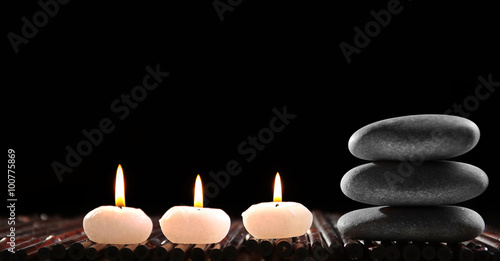 Spa still life with stones and candles in water on black background