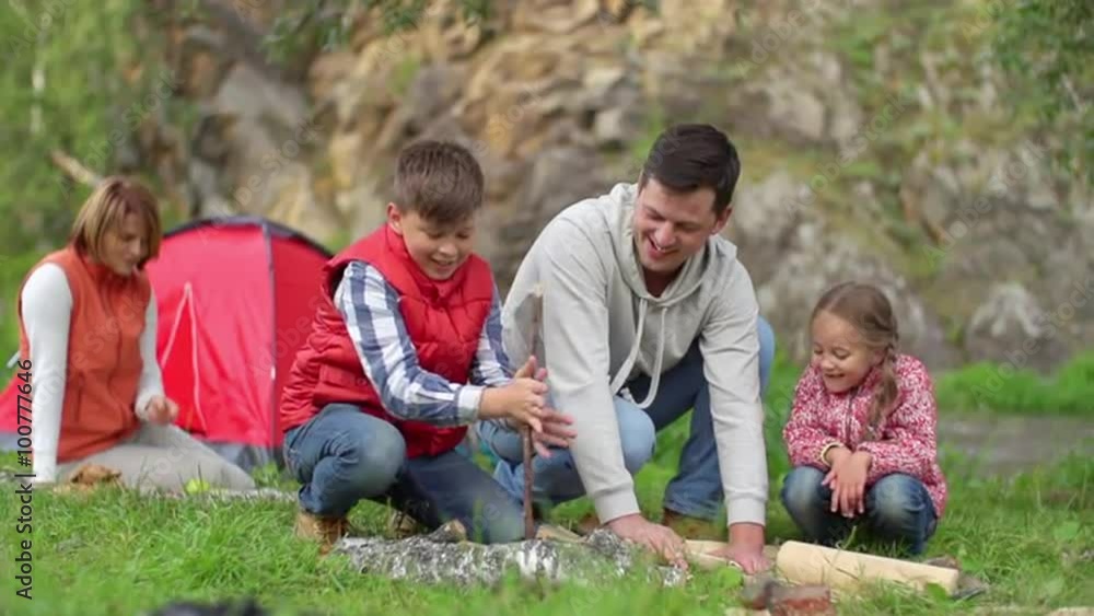 Father teaching his kids how to start fire with sticks in the forest Father teaching his kids how to start fire with sticks in the forest
