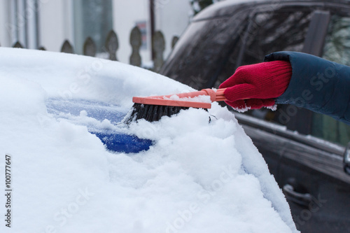 Hand of woman using brush and remove snow from car and windscreen