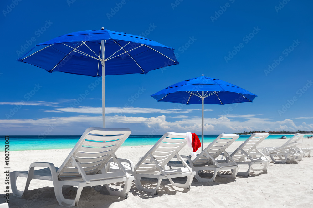 Caribbean beach with blue sun umbrellas and white sunbeds