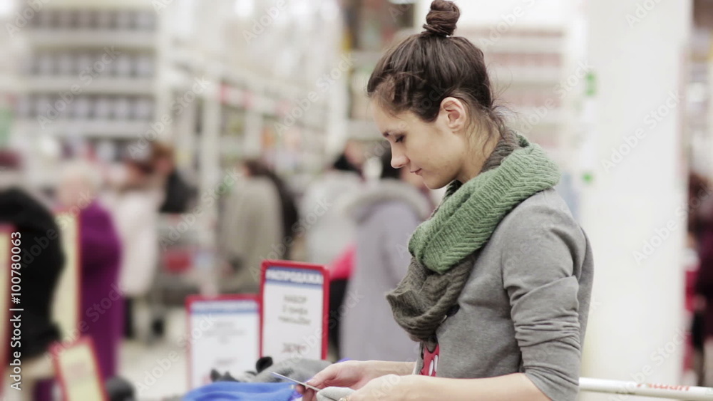 Young woman chooses winter hat in the supermarket Young woman chooses winter hat in the supermarket