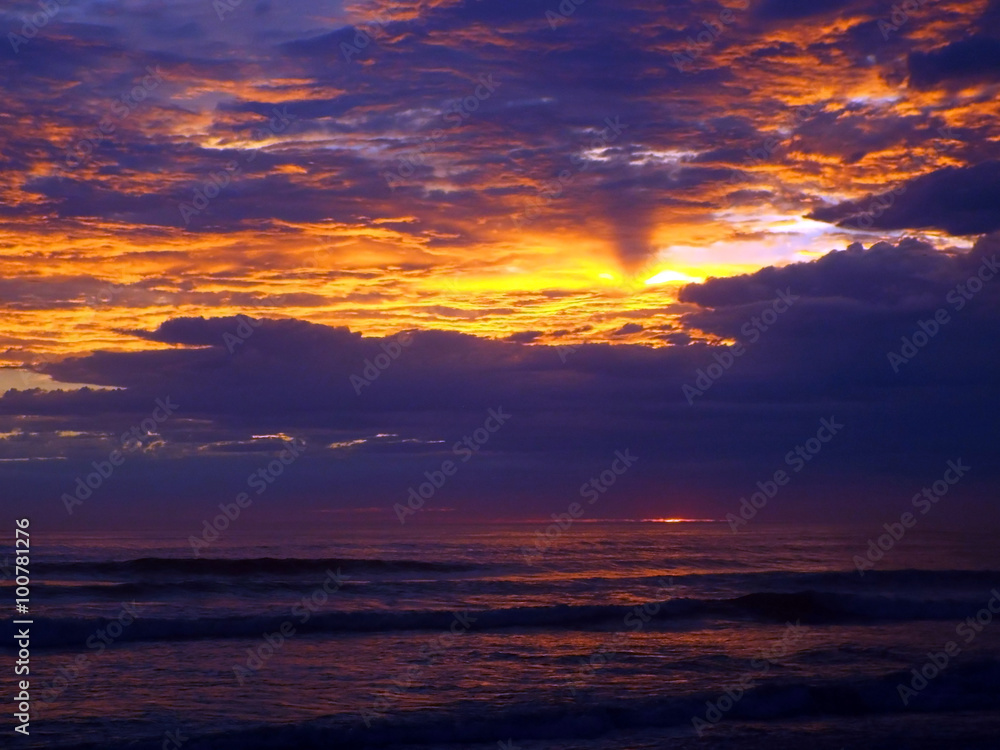 Cloudy Sunset Over the Ocean with Waves in the Foreground