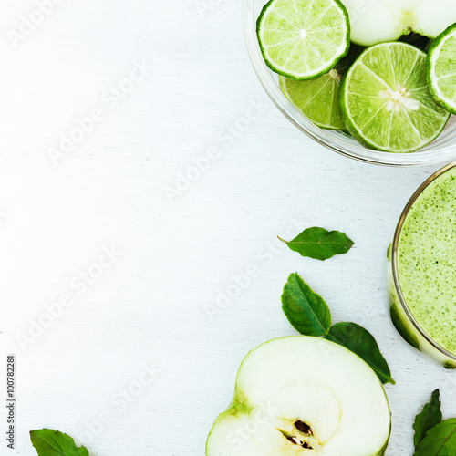 Vegetable juice, apple, sliced lime on the white wooden backgrou