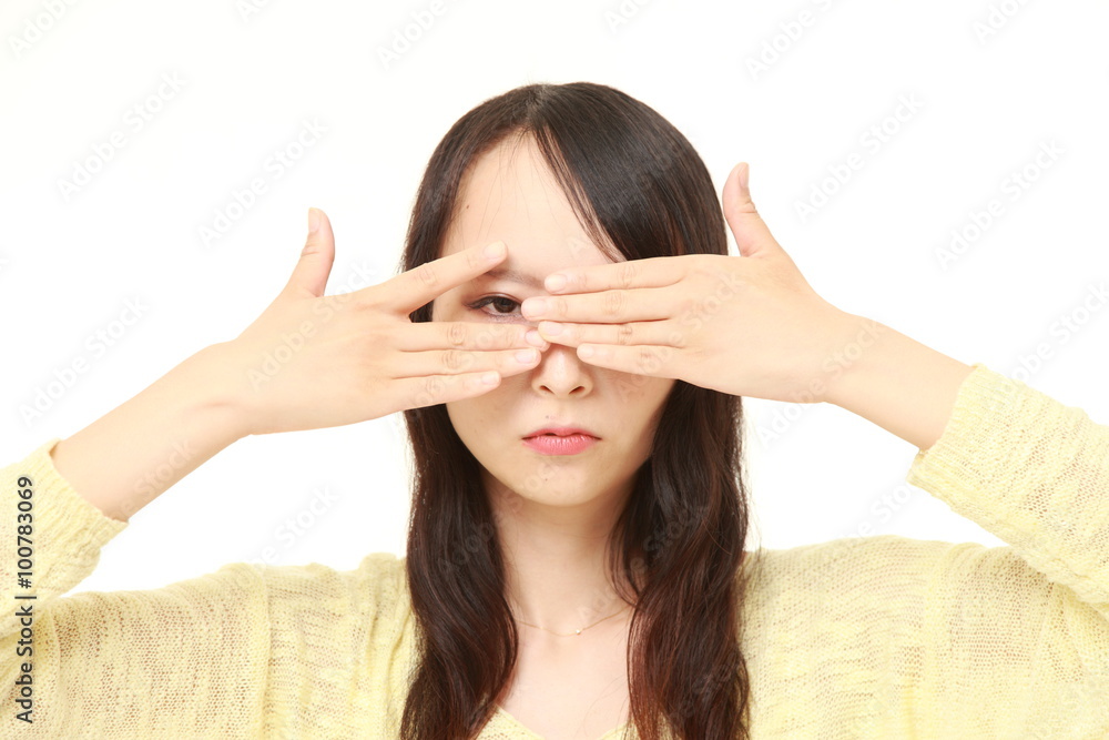 Japanese woman covering her face with hands peeping at the camera through her fingers Japanese woman covering her face with hands peeping at the camera through her fingers