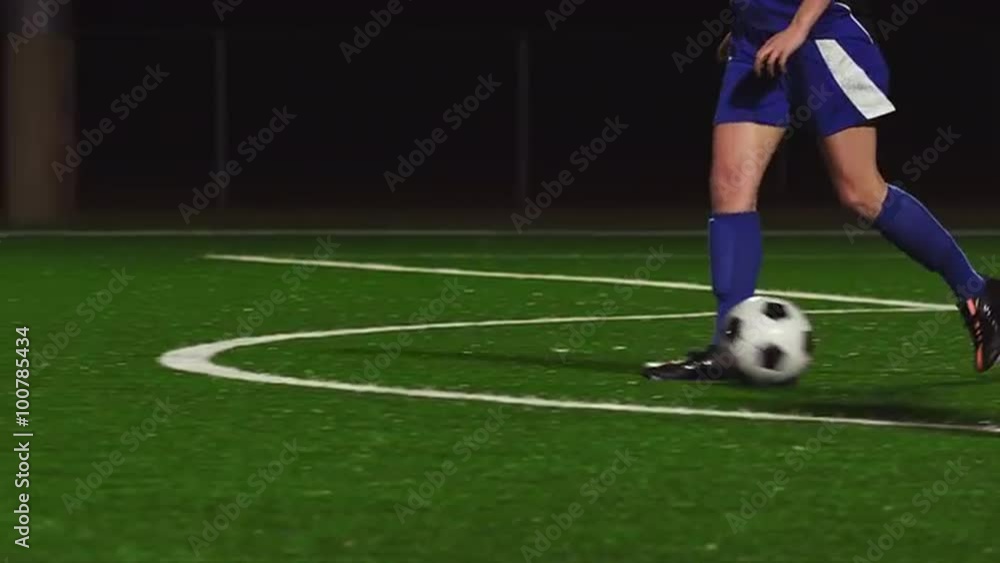 Female soccer players dribbling down the field during a game at night Female soccer players dribbling down the field during a game at night