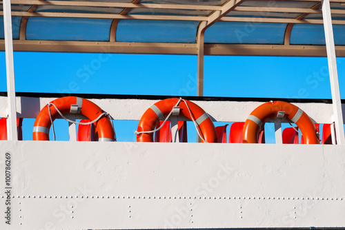 Lifebuoys in a Ferry Boat / A row of red and orange life buoys on the deck of a passenger ship