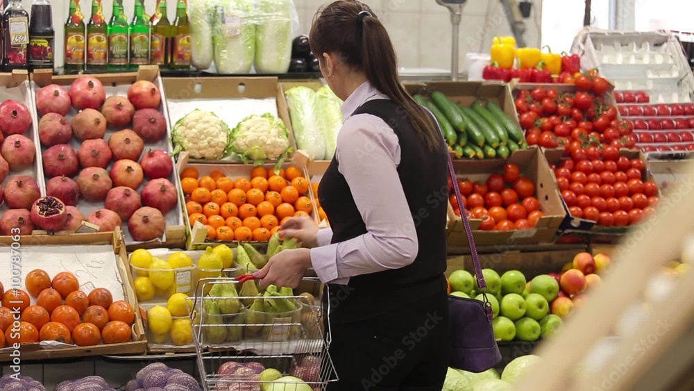 Woman selecting fruit at market and adds to cart, rear view Woman selecting fruit at market and adds to cart, rear view