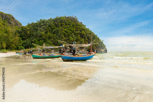 Samphraya Beach in Thailand, fishing boat parked on beach, background is blue sky © dewspliff