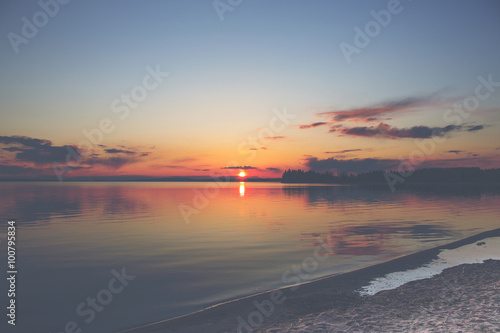 A magnificent sunset by the lake in Finland. Image has a vintage effect applied.