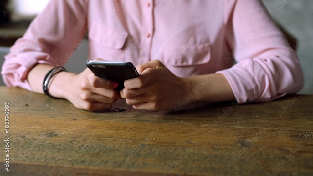 Closeup of woman using smartphone on wooden desk at cafeteria Closeup of woman using smartphone on wooden desk at cafeteria
