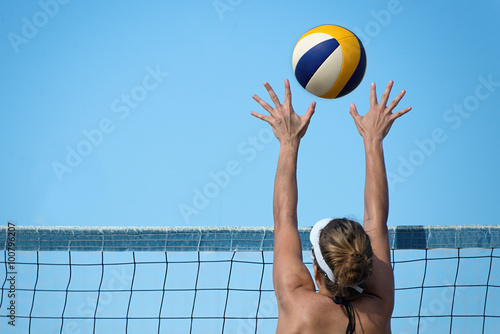 Beach volleyball player jumps on the net and tries to blocks the ball