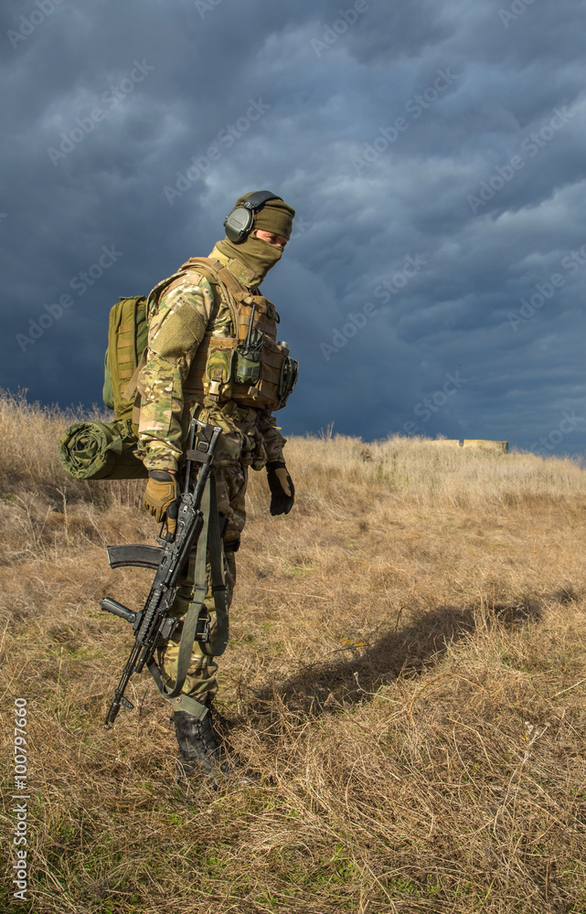 Military doctor with a gun standing in a field in the rays of the setting sun Military doctor with a gun standing in a field in the rays of the setting sun