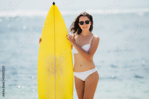 Beauitful young surfer girl going to the waves with her surfboard